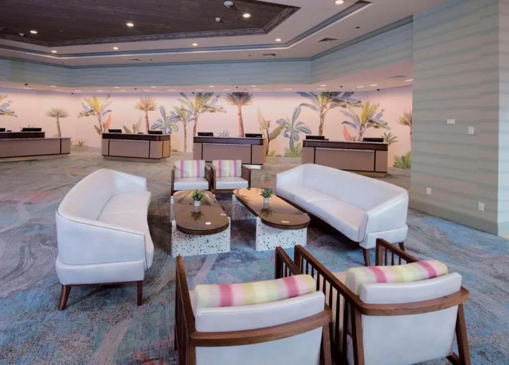 Sof&aacute;s blancos y un mural de palmeras detr&aacute;s de los mostradores de facturaci&oacute;n en Caribe Royale Orlando