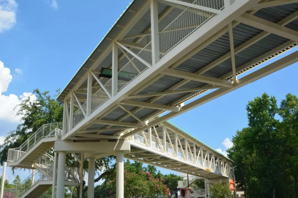 White steel skybridge with stairways and a green roof, seen from below at Rosen Plaza Hotel