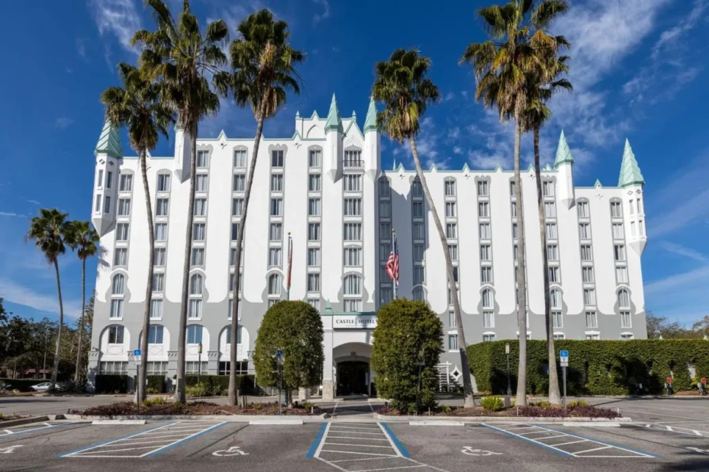 White turreted facade of Castle Hotel, Autograph Collection in Orlando behind tall palm trees