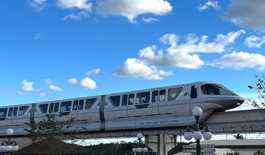 White Walt Disney World monorail train gliding along its elevated beam under a bright blue sky