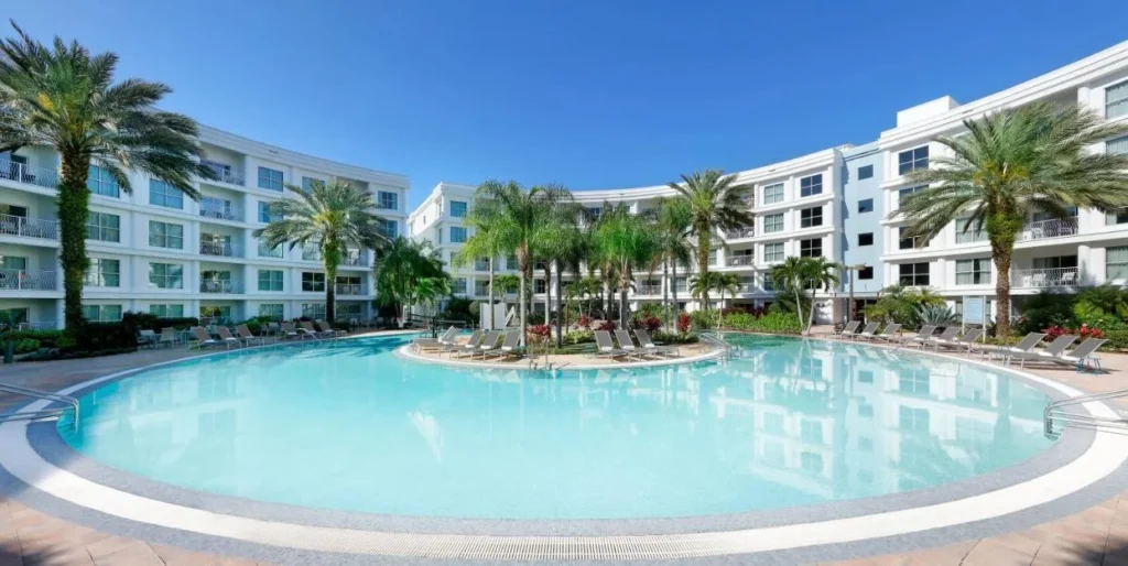 Amplia vista de la piscina al aire libre rodeada de edificios blancos en Meliá Orlando Celebration