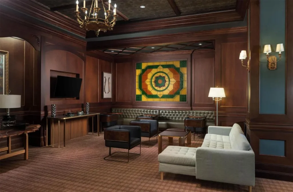 Salón de paneles de madera con banqueta de cuero, sillones y un panel de vitrales en Waldorf Astoria Orlando