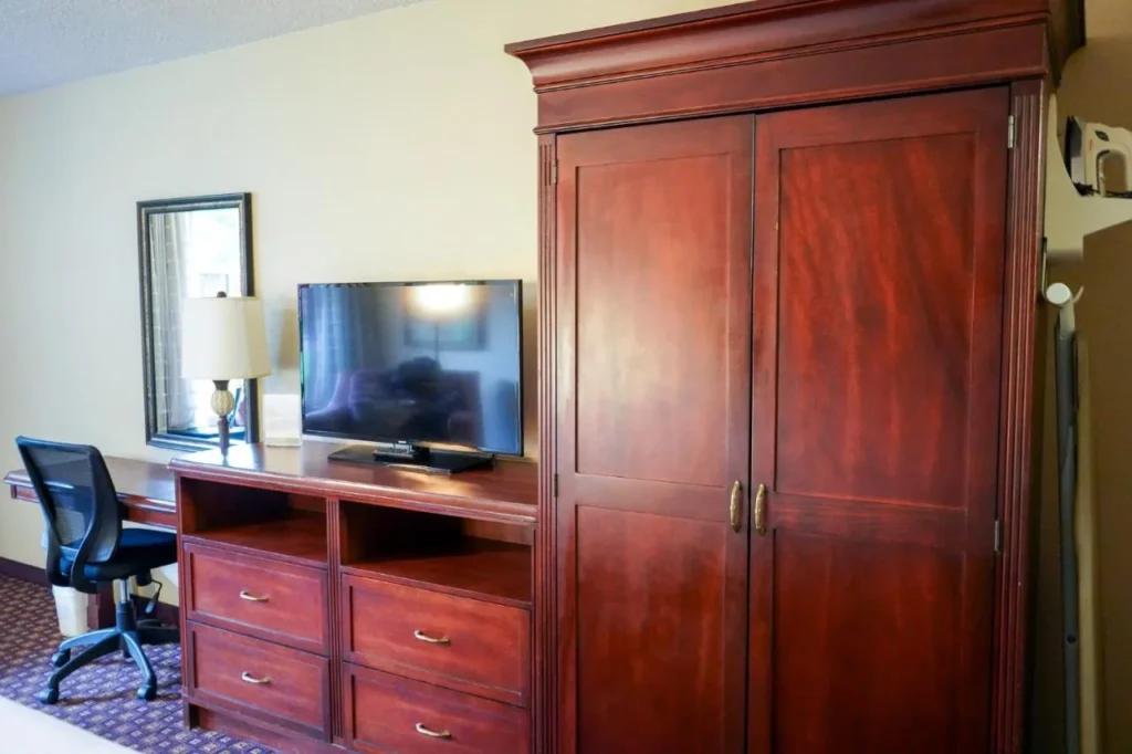 Armario de madera, TV de pantalla plana y escritorio en una habitación en Rosen Inn at Pointe Orlando