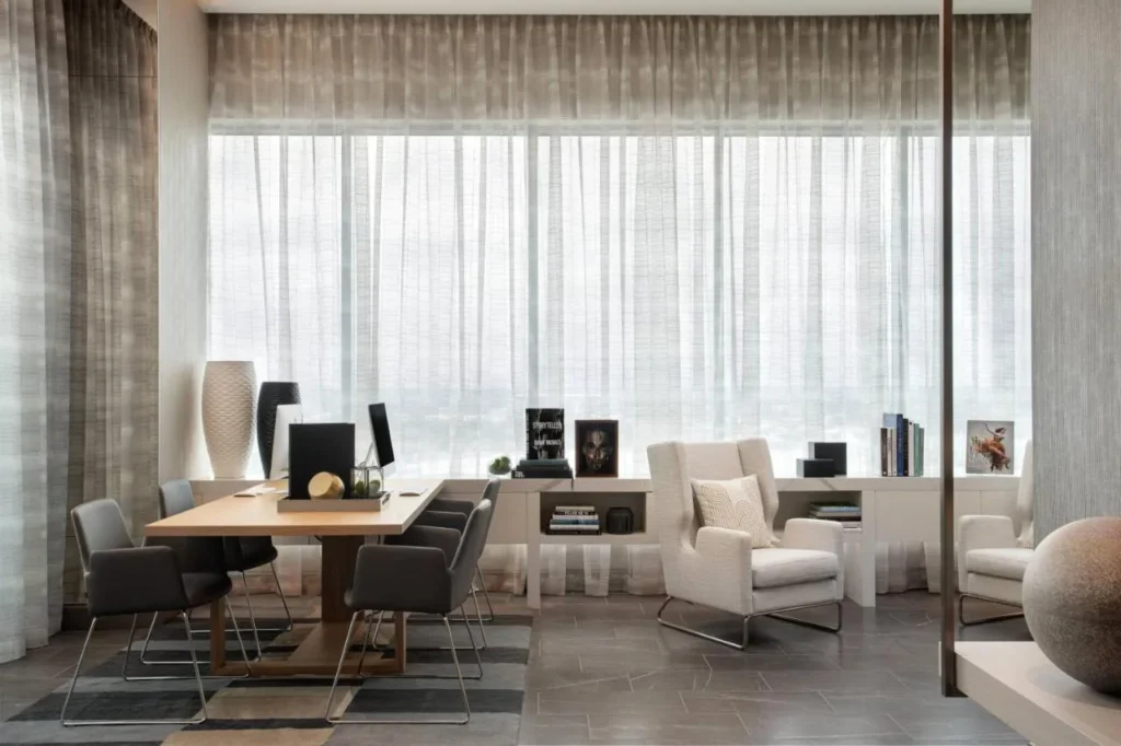 Área de trabajo con mesa compartida, computadoras y sillones en AC Hotel Orlando Downtown