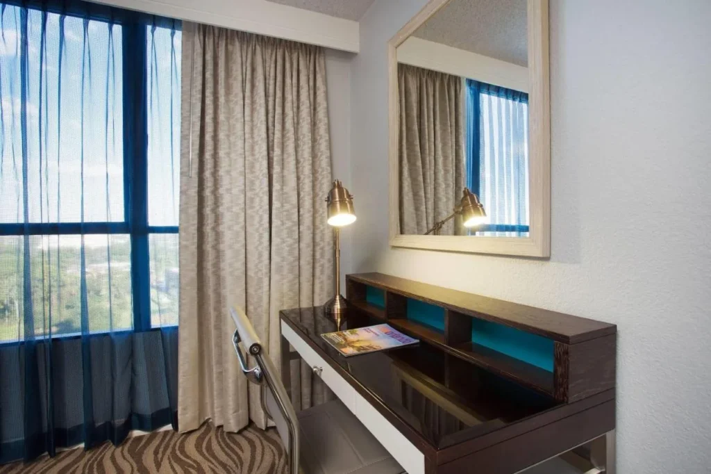 Work desk, mirror and tall window in a tower room at Wyndham Lake Buena Vista