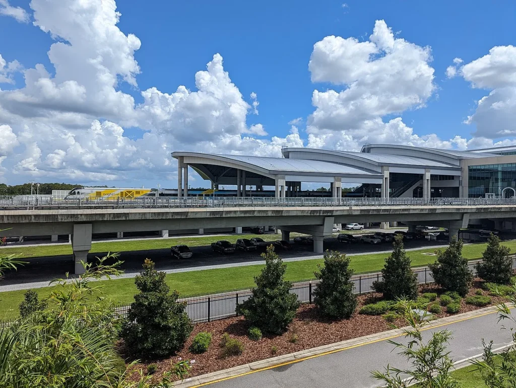 Yellow Brightline train beside the curved white roofs of the Orlando airport train station