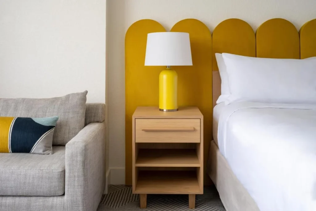 Cabecero amarillo, l&aacute;mpara y sof&aacute; gris junto a una cama en Renaissance Orlando Resort and Spa