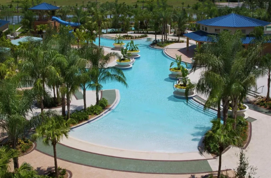 Piscina de entrada cero bordeada de palmeras y jardineras, con un tobogán más allá, en Hilton Orlando
